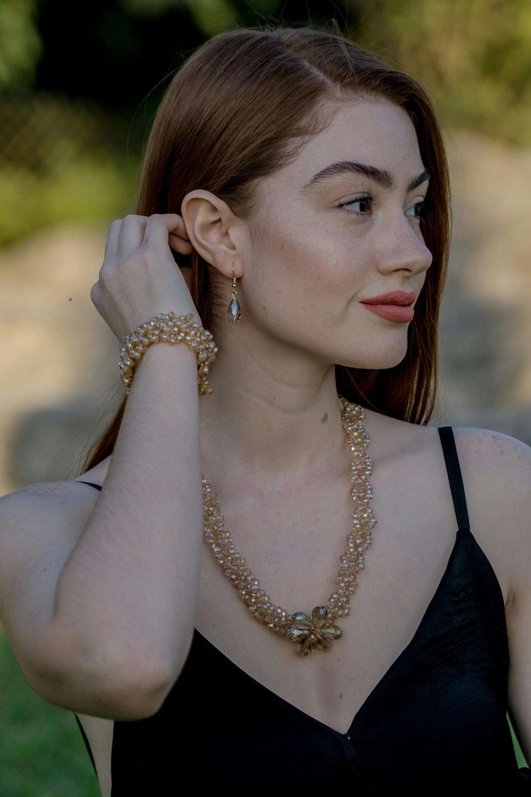 A stylish woman wearing a necklace and bracelet outdoors during the day.
